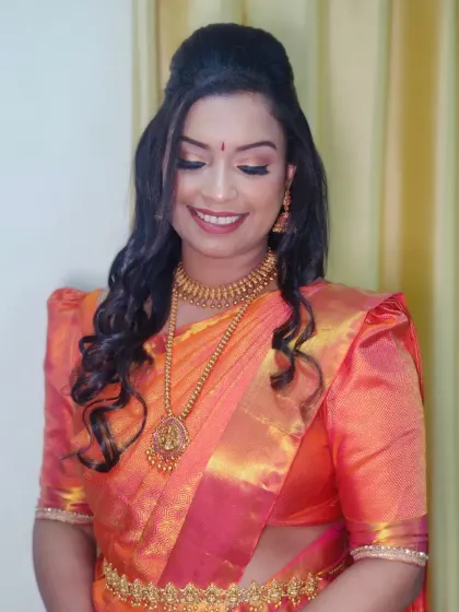 A beautiful South Indian makeover, featuring a dual-toned orange silk saree, gold shimmer eyes, and deep nude lipstick.