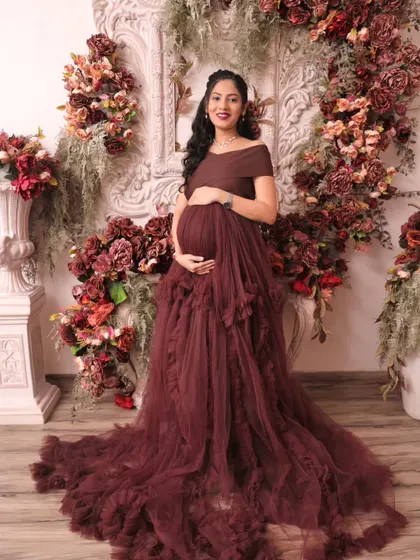 The expecting mother stands confidently, cradling her bump. Our floral backdrops are designed to complement your outfit and enhance the beauty of the portrait.
