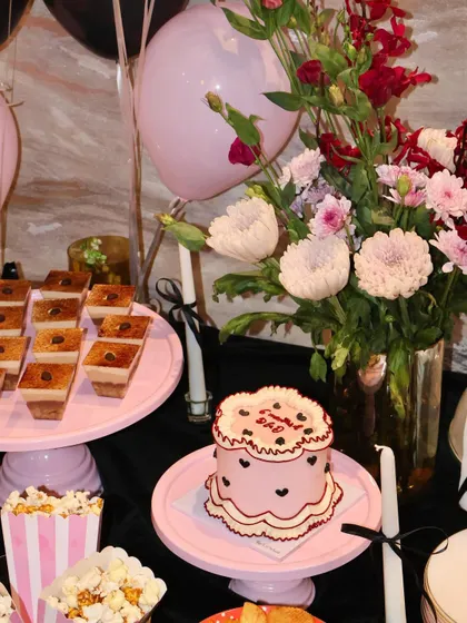 A lovely view of our dessert table featuring a custom pink heart-themed mini cake alongside our popular Tiramisu cups. We love coordinating the desserts with the party's floral arrangements and color scheme.