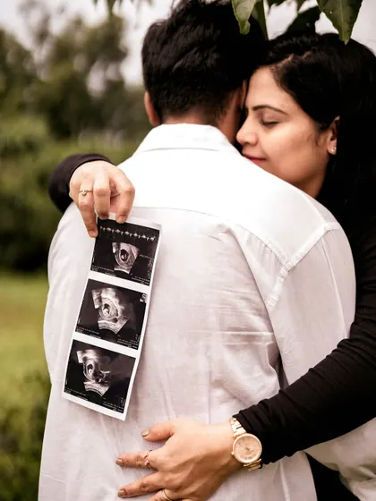 An intimate close-up of the mom-to-be hugging her partner from behind, holding the sonogram pictures against his back. It’s a creative and loving way to include the baby in their embrace.