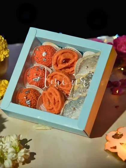 My Mithai Candle Gift Box, elegantly packaged in a pastel blue box with a clear window. This packaging is designed to showcase the intricate details of the Laddoo, Jalebi, and Kaju Katli candles inside, making it a perfect ready-to-gift option.