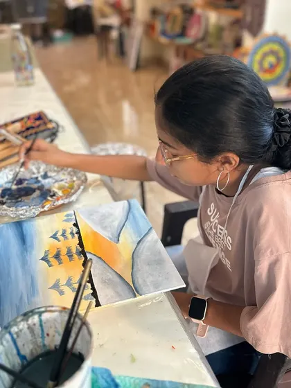 A young artist working on her forest landscape. The colors of the sunset are blending beautifully.