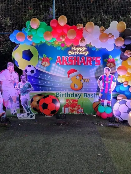Akshar's 8th birthday football party setup on a turf, with a stadium backdrop and cutouts of famous football players.
