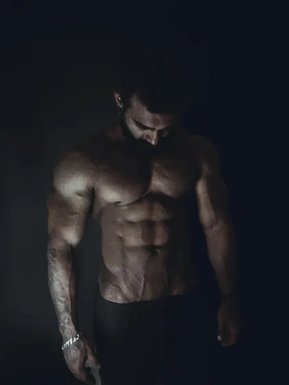 A similar moody shot, showing the vascularity in the arms and the deep cuts in the abs.