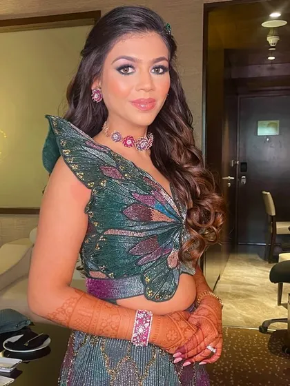 A fun and flirty sangeet look with soft waves and a butterfly-themed top.