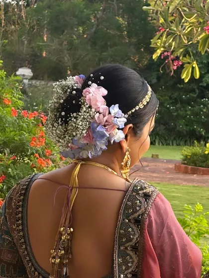 A detailed close-up of the bridal bun, featuring intricate braids and a beautiful arrangement of fresh baby's breath and pastel hydrangeas. I teach how to work with fresh flowers to create stunning bridal hair.