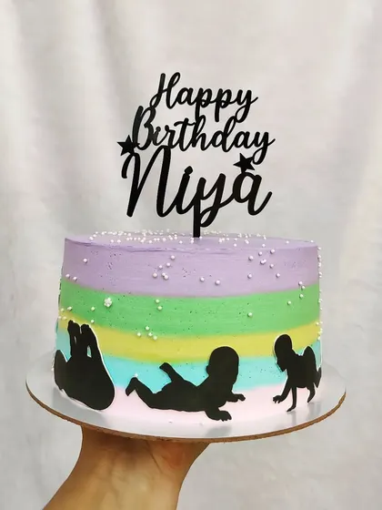 This cake represents a baby's journey through their first year, with silhouettes showing the stages of development on a pastel rainbow background.