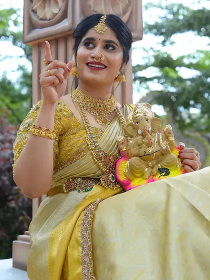 A happy, festive shot of a model with a Ganesha idol, wearing our traditional gold-look alike jewellery.