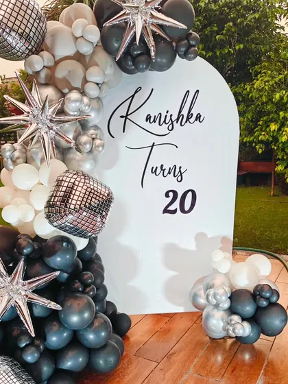A closer view of the sophisticated 20th birthday decor. The black, white, and silver balloons with starburst accents create a very modern and celebratory feel.