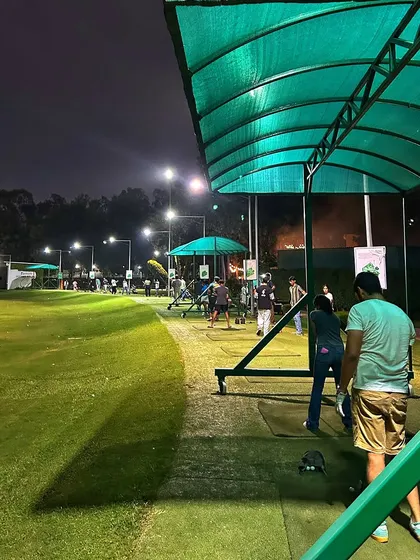 Another perspective of the bustling night range, with the green awnings and bright lights creating a welcoming atmosphere.