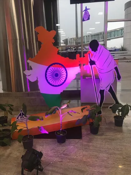 This patriotic installation features a cutout of Mahatma Gandhi alongside the map of India, illuminated with purple light. It's a powerful and artistic setup for a corporate or public event.