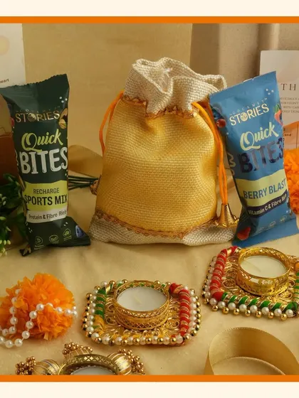 This festive gift set includes two decorative diyas and healthy snacks in a potli bag, combining tradition with modern wellness.