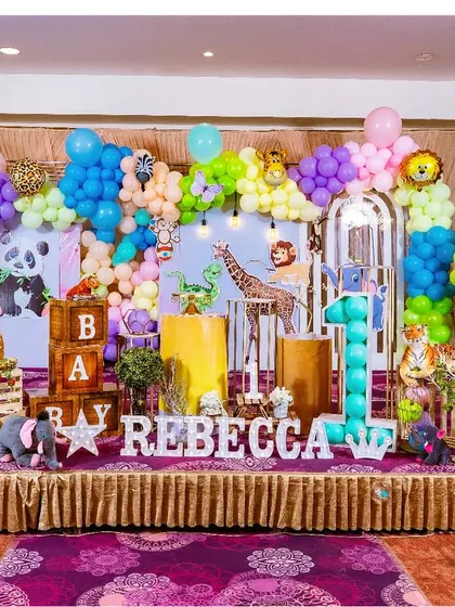 A colorful and playful jungle theme with a pastel twist. The use of purple and pink balloons alongside the traditional green and brown gives this setup a unique look.