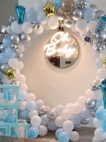 An elegant and modern 'Oh Baby' setup, perfect for a baby shower or welcome home party for a boy. This design is built around a full circular balloon arch in pastel blue, white, and chrome silver, with a central neon sign. I also include themed props like 'BABY' display boxes and foil balloons shaped like baby bottles.