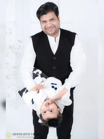 A playful father holds his daughter upside down, both of them having fun. This candid shot captures the joyful and silly moments of family life.