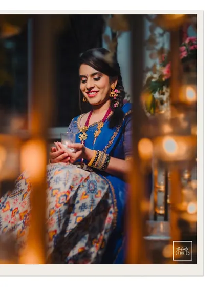A beautiful portrait of a bride holding a diya, her face illuminated by the warm candlelight, creating a serene and spiritual feel.