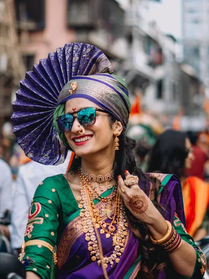 A woman dressed in a traditional Maharashtrian saree and a grand 'pheta' (turban) smiles during the Gudi Padwa 'Shobhayatra' in Mumbai. The image is a beautiful celebration of culture and female empowerment.