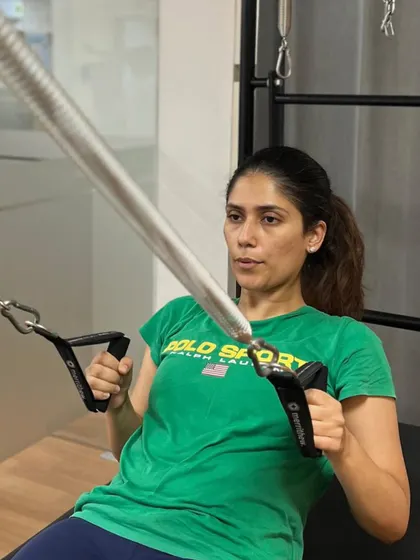 A member uses the Cadillac for an arm-pulling exercise, focusing on upper body strength and scapular stability.