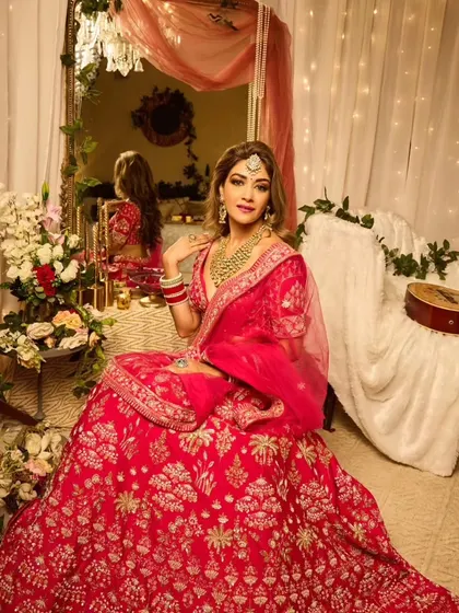 Full Hollywood glam for this bride. The look features voluminous side-swept waves, a smokey eye, and a vibrant pink lehenga, creating a stunning and memorable style for any wedding event.