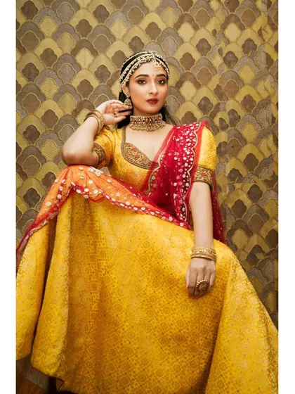 A full view of a model in a yellow lehenga, adorned with our choker set. This shows how our traditional pieces can also be styled with lehengas.