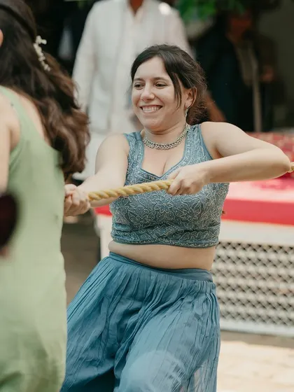 A guest pulls on the rope with a huge smile, fully immersed in the fun and games of the Mehendi party.