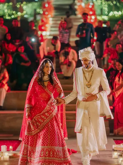 The couple walks hand-in-hand after their Varmala, surrounded by the warm glow of hundreds of candles placed around the ceremony space.