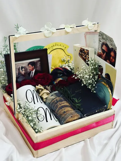 The anniversary hamper in a handled pinewood tray, making it easy to present. The combination of personalized items and treats makes it a truly special gift.