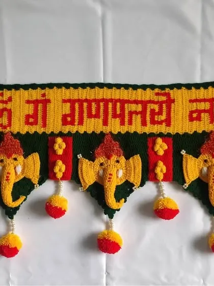 A full view of the classic Ganpati toran against a white background, showcasing the entire design with five Ganpati motifs and hanging pom-poms.