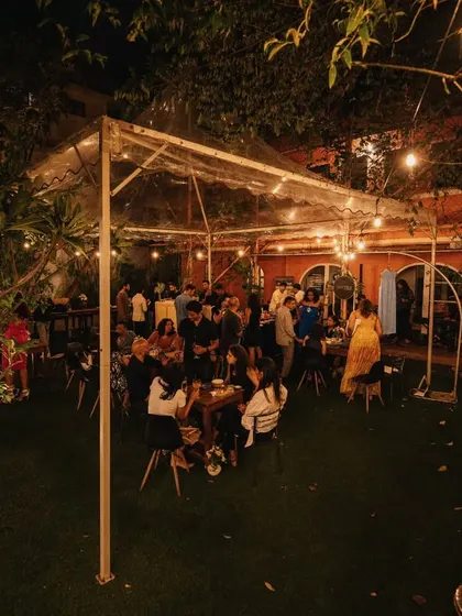 Another view of the outdoor garden party, showing guests mingling under the warm glow of the lights.