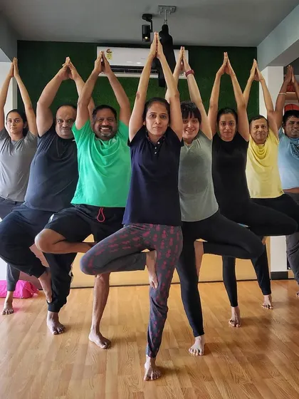 A group of men and women holding Tree Pose together, demonstrating that yoga is for everyone.