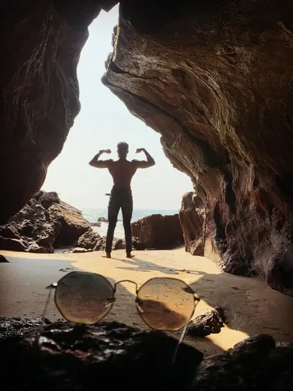 "Love yourself first." A creative shot posing inside a beach cave, with sunglasses in the foreground.