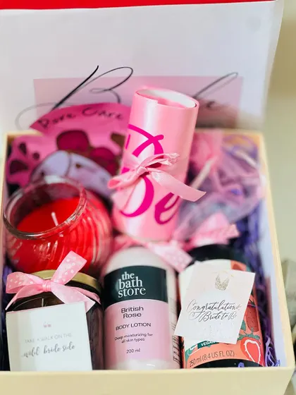 A close-up of the items inside the 'Bride to be' hamper. You can see the 'Bride' sash, scented candle, body lotion, and other carefully selected gifts.