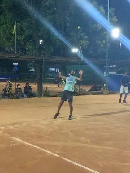 A dynamic serving motion captured under the floodlights. The atmosphere at night is energetic, perfect for a focused practice session or a competitive game.