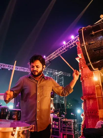 Playing a large, mounted bass drum at an outdoor festival. This instrument adds a deep, resonant boom that is perfect for high-energy festival anthems.