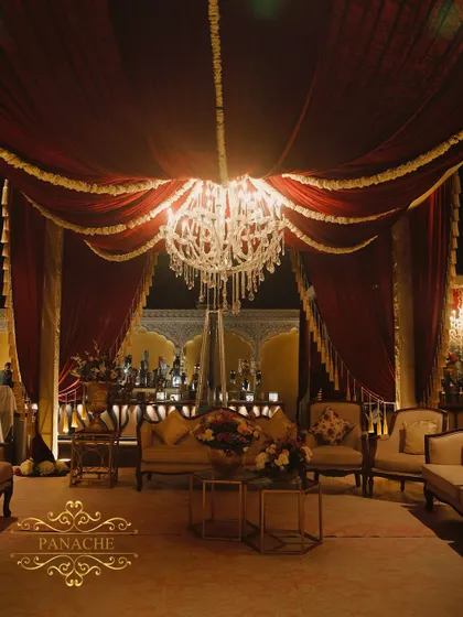 A cozy and regal seating arrangement under a draped canopy, with a well-lit bar in the background. We design these spaces to be both beautiful and functional for guest comfort.
