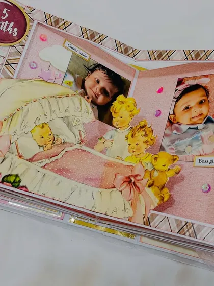 A pop-up element inside the baby album, showing the '5 months' milestone with vintage-style baby illustrations.