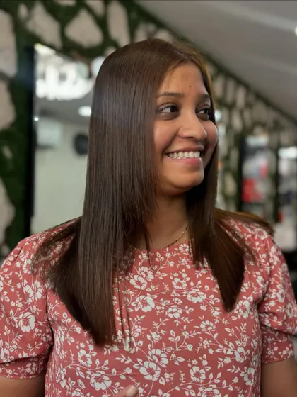 A happy client showing off her smooth, healthy, and shiny hair after one of our signature smoothening treatments.