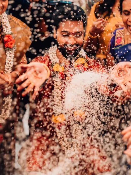 The groom is showered with rice and blessings during a vibrant wedding ceremony.