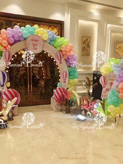 A dreamy hot air balloon themed entrance, featuring a circular arch made of pastel rainbow balloons and charming hot air balloon cutouts.