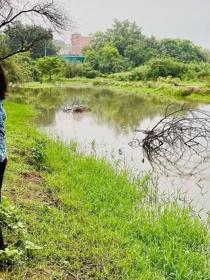 A participant on our community walk pauses to enjoy the serene view of the water body at Ghata Bundh, a testament to nature's ability to heal.