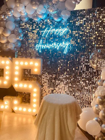 Celebrating 25 years in style. For this silver jubilee anniversary, we used a silver sequin wall, a "Happy Anniversary" neon sign, and large marquee numbers to create a dazzling and memorable setup.