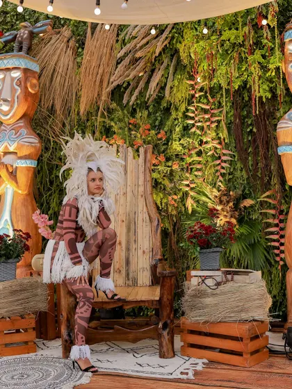 A performer in a dramatic, tribal-inspired costume poses on a rustic wooden throne. This kind of interactive entertainment adds a dynamic and memorable element to the event.