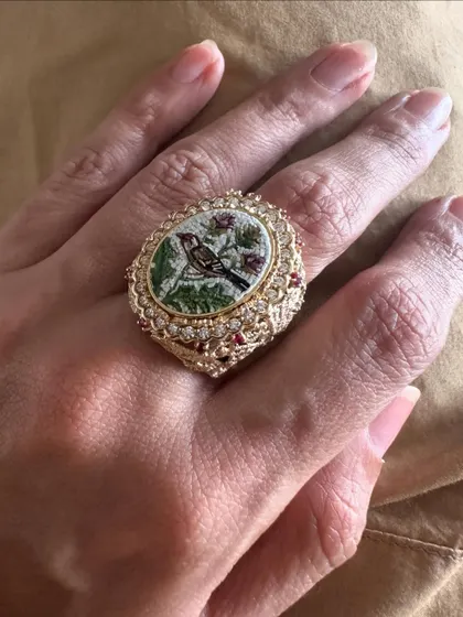 A micromosaic ring featuring a sparrow perched on a branch. The intricate details of the bird and leaves are set within an ornate 18k gold and diamond frame, making it a unique statement piece.