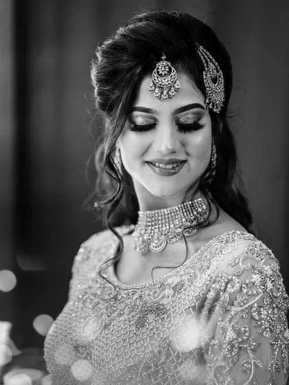 A serene black and white bridal portrait. The soft focus and her gentle smile create a dreamy and glamorous image, highlighting her beauty and poise.