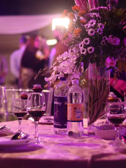 The ambiance at Thiago's communion was magical. This photo captures the soft purple lighting on the tables, with a beautiful floral centerpiece and wine glasses ready for a celebratory toast.