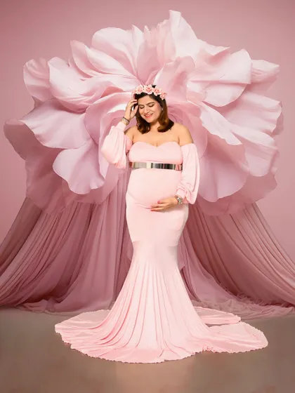A stunning solo portrait featuring a form-fitting pink gown against a giant pink paper flower backdrop. This setup creates a dramatic, high-fashion look that is incredibly memorable.