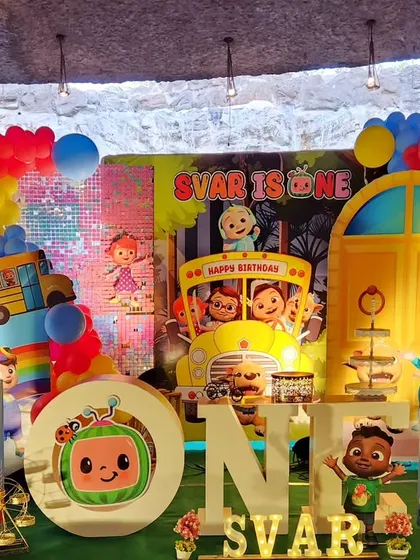 A vibrant and colorful Cocomelon first birthday party. This large-scale setup features the iconic yellow school bus, JJ and his friends, and a rainbow of balloons to create a cheerful atmosphere.