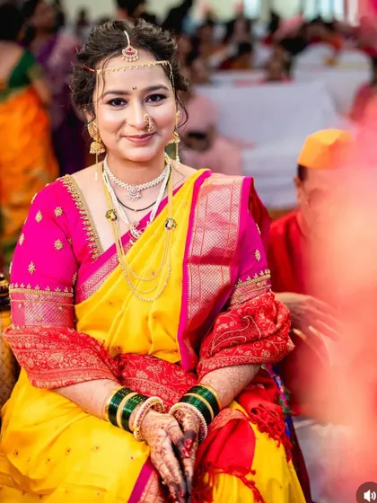 A radiant bride during her wedding ceremony. She wears a traditional yellow saree with a pink blouse, her makeup soft and glowing.