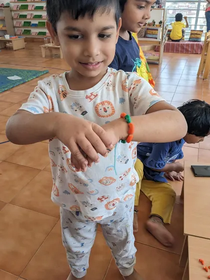A child shows off a bracelet made during a summer camp craft session. Activities like beading are excellent for developing fine motor control and pattern recognition.