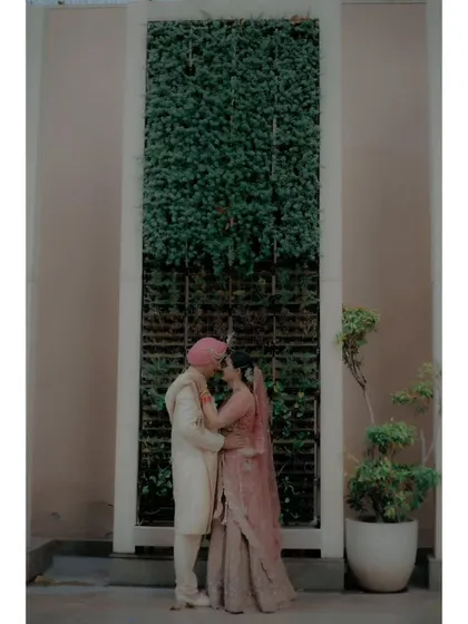 The couple shares an intimate moment in front of a green wall, their embrace full of warmth and affection.